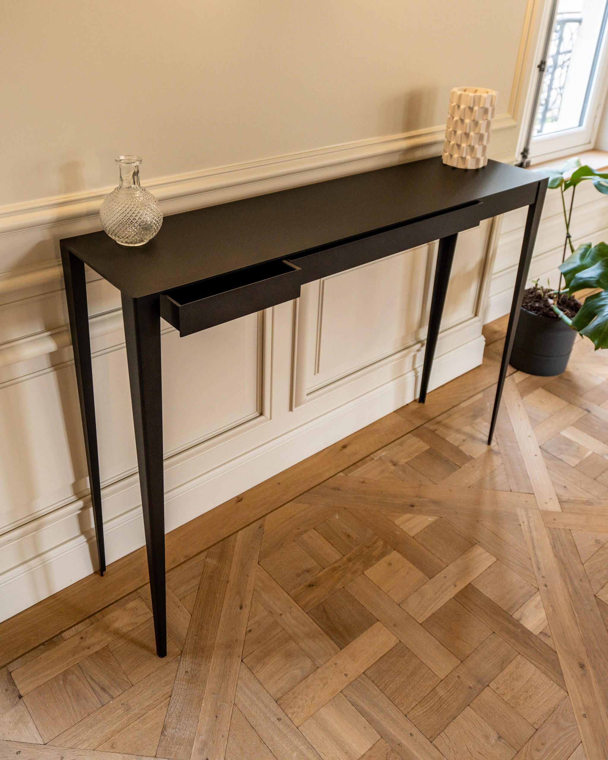 Console Manon noire avec un tiroir ouvert sur parquet